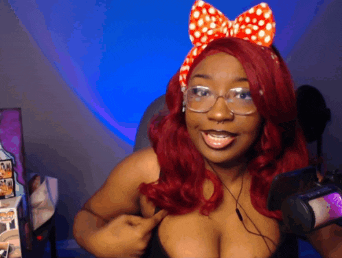 a woman with red hair and glasses is wearing a red and white bow headband