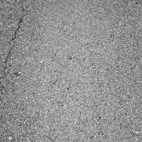 a black and white photo of a cracked asphalt road texture .