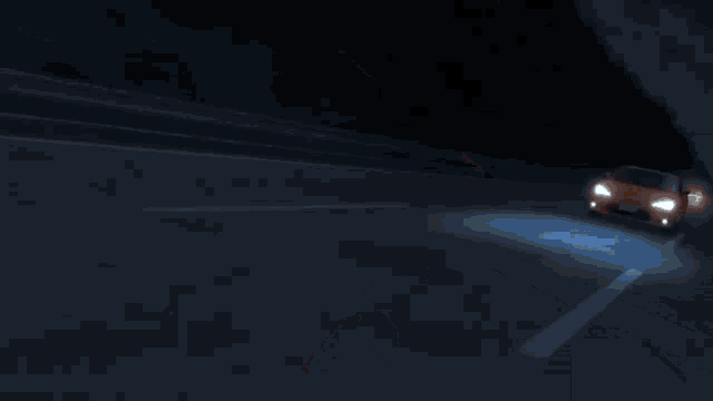 a car is driving down a road at night with its headlights on