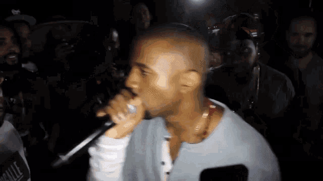 a man is singing into a microphone while a crowd watches .