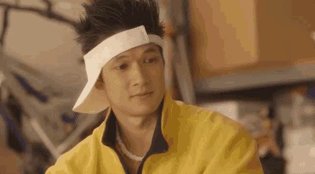 a man wearing a yellow jacket and a white headband is looking at the camera .