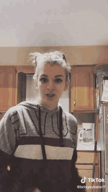 a woman in a kitchen wearing a hoodie that says ' nvc ' on it