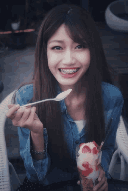 a girl with braces on her teeth is eating ice cream