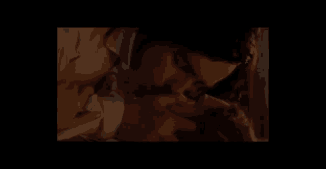 a man kissing another man on the cheek in a dark room
