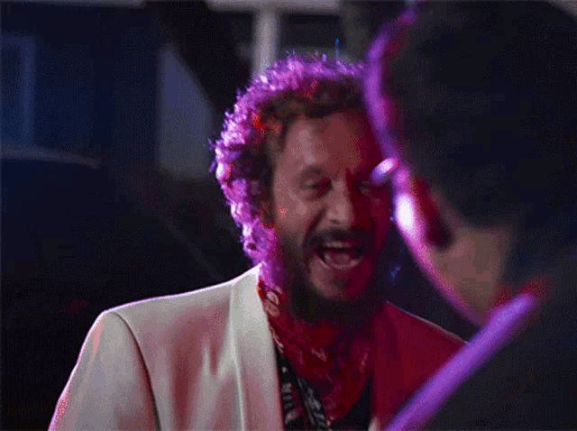a man with a beard wearing a white jacket and a red bandana