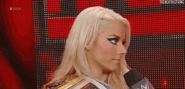a female wrestler is talking into a microphone on a red background .