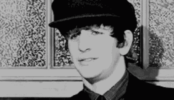 a black and white photo of a young man wearing a hat and a suit .