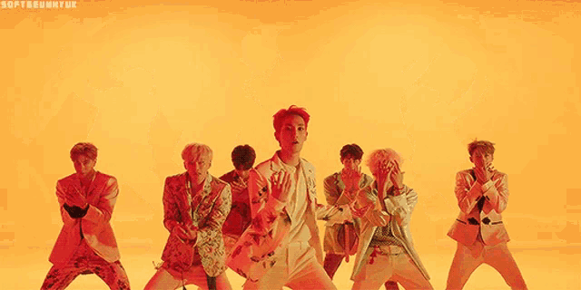 a group of young men are standing next to each other in front of a yellow background .