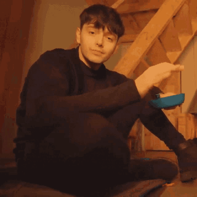 a young man sitting on the floor holding a blue object