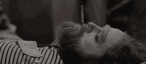 a man with a beard is laying down with a dollar bill in his pocket ..