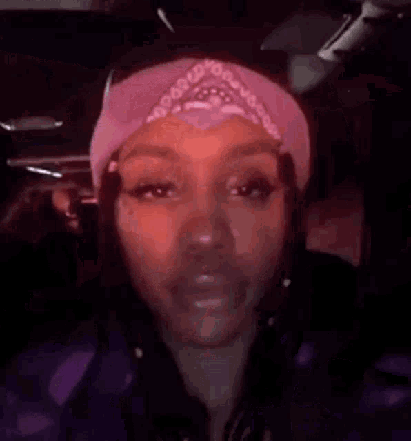 a woman wearing a bandana and a headband is holding her head and saying welcome .