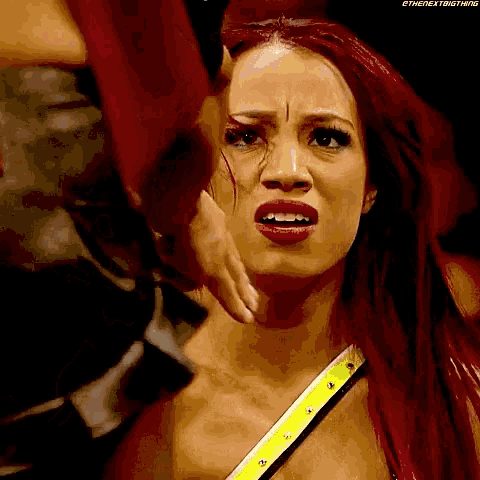 a woman with red hair is being held in a wrestling ring by a man .