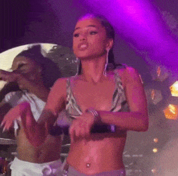 a woman in a crop top is holding a microphone on stage .