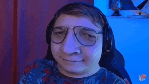 a man wearing glasses and headphones is sitting in a chair and smiling .