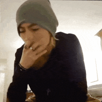 a woman wearing a gray beanie and a black shirt with a cross on it