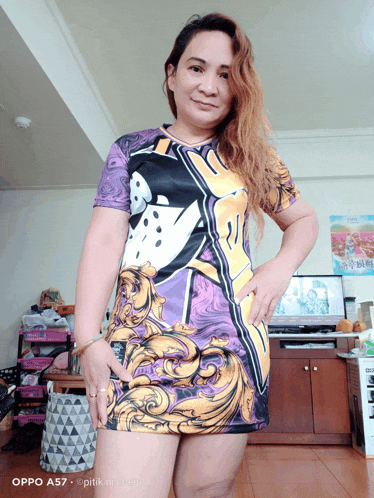 a woman in a purple and gold dress is standing in a living room with her hands on her hips