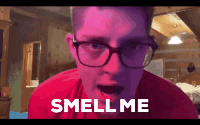a man with glasses and a red shirt is saying smell me