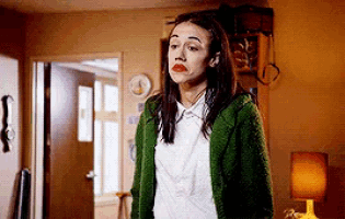 a woman wearing a green sweater and a white shirt is standing in a living room .