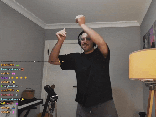 a man wearing headphones and a black shirt is dancing in front of a keyboard and a guitar