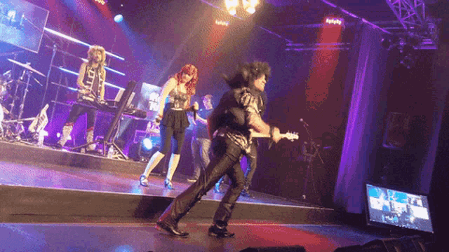 a man playing a guitar on a stage in front of a group of people