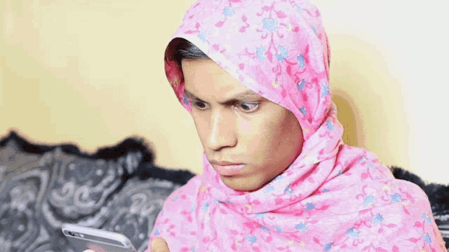 a woman wearing a pink hijab is looking at her phone