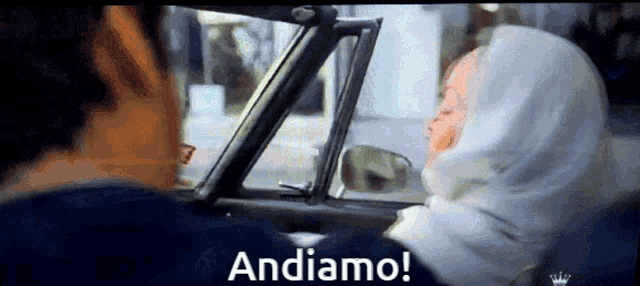 a woman in a hijab is sitting in a car with the words andiamo on the bottom