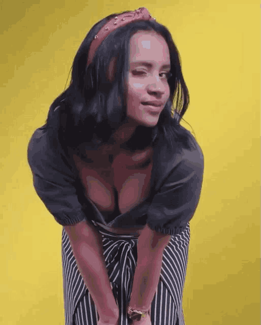 a woman wearing a striped skirt and a plunging neckline shows off her cleavage