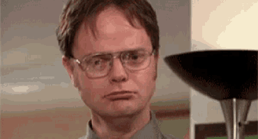 a man wearing glasses is standing in front of a lamp and making a funny face .