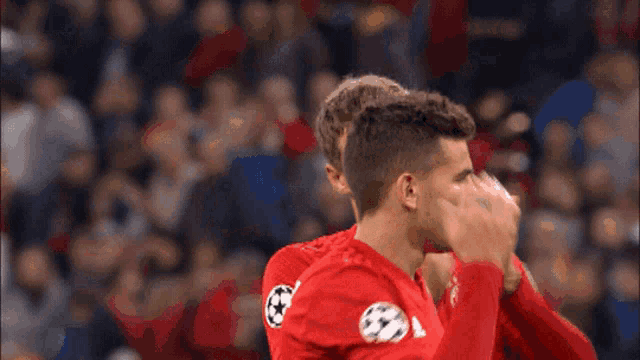 a soccer player wearing a red adidas jersey is clapping his hands