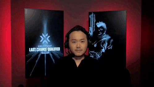a man wearing headphones is standing in front of a monitor that says last chance qualifier .
