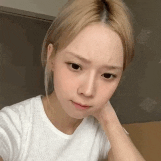 a young woman with blonde hair is wearing a white t-shirt and looking at the camera .
