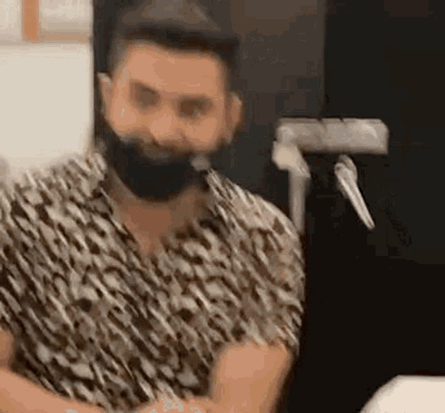 a man with a beard is wearing a mask while sitting at a table .