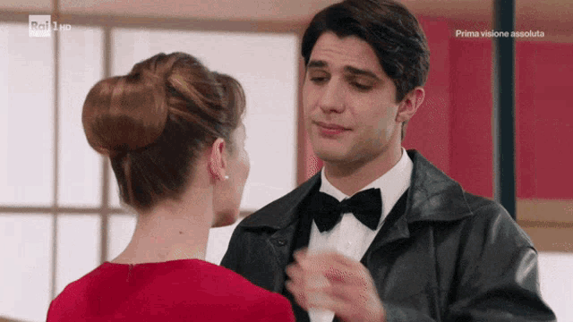 a man in a tuxedo and bow tie is dancing with a woman