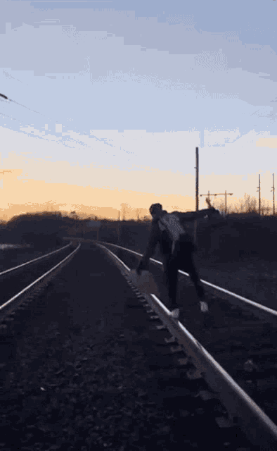 a person walking on train tracks with a shirt that says ' i love you ' on it