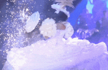 a person in a white dress is surrounded by snow and feathers