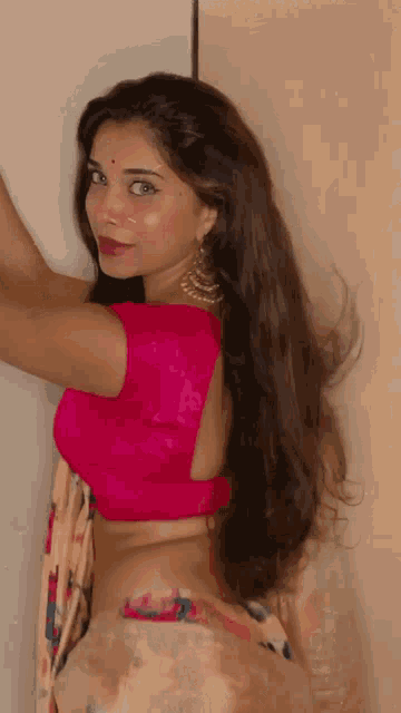 the woman is wearing a pink blouse and a floral printed skirt