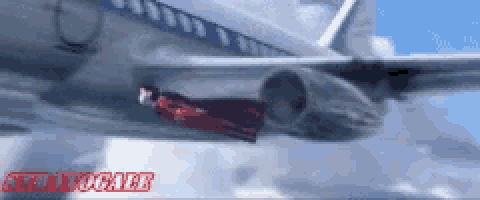 a man in a red suit is flying under the wing of an airplane