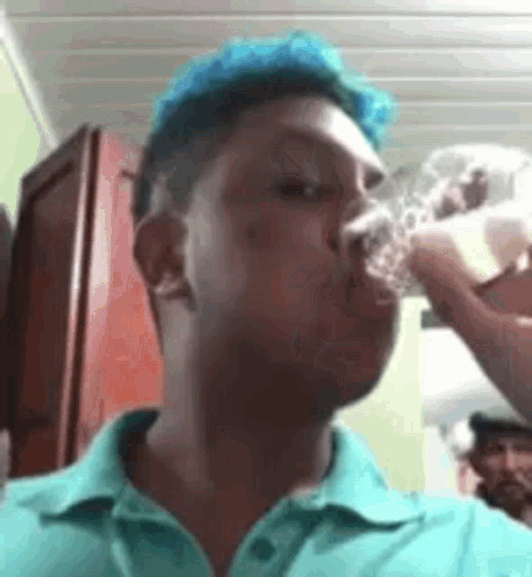 a man with blue hair is drinking a glass of water .