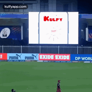 a cricket game is being played in front of a large screen that says kulfy out