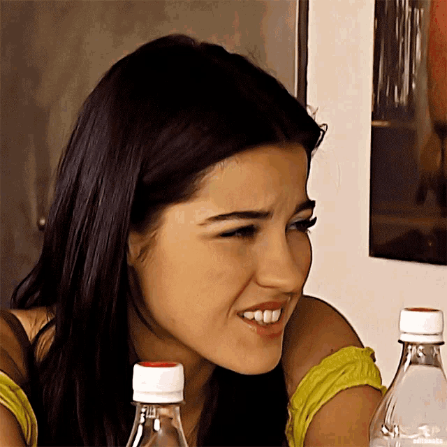 a close up of a woman 's face with two water bottles in the background