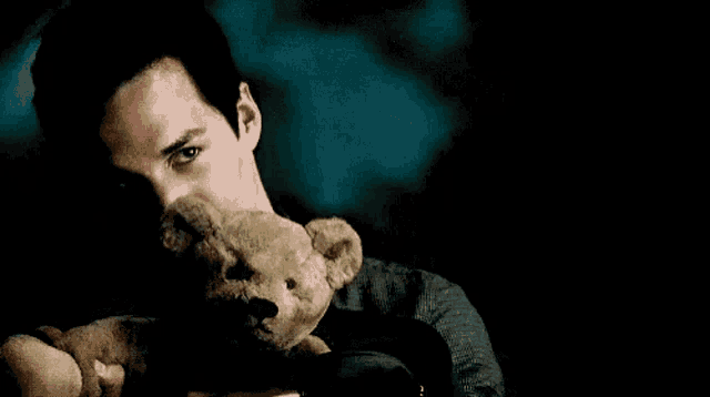 a man is holding a teddy bear in his arms