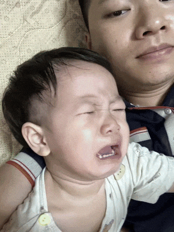 a baby is crying while being held by a man on a bed
