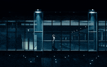 a woman is standing in front of a large glass wall
