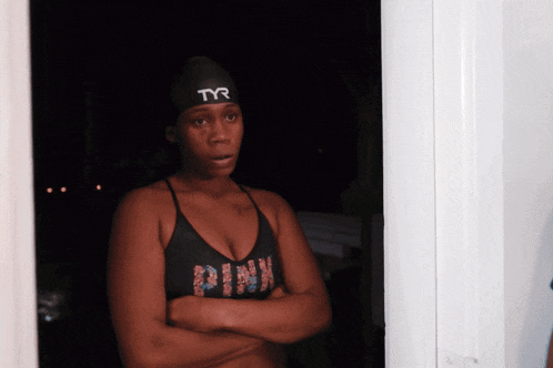 a woman in a pink tank top and a black tyr swim cap