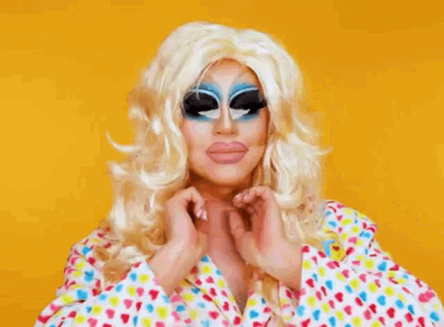 a drag queen is wearing a wig and sunglasses and making a face .