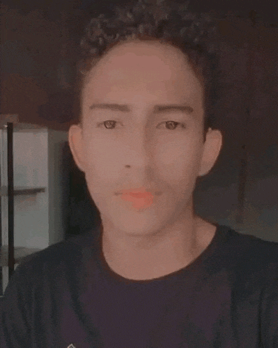 a young man with curly hair is wearing a black shirt and taking a selfie .