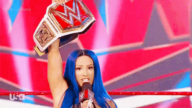 a woman with blue hair is holding a wrestling championship belt in her hand .