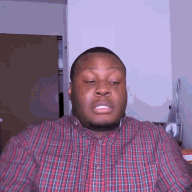 a man in a plaid shirt is making a face