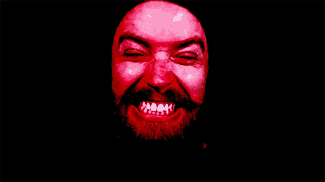 a man with a beard has a red face and white teeth