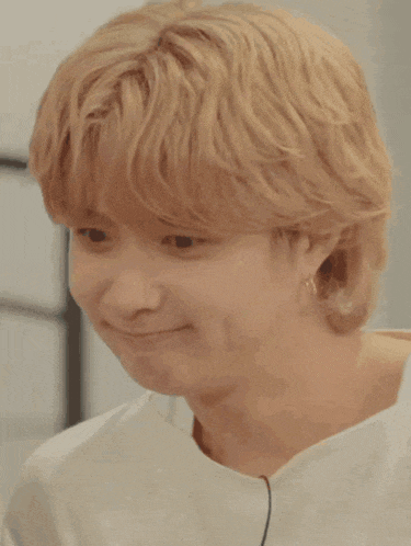 a close up of a person 's face with blonde hair and a white shirt .